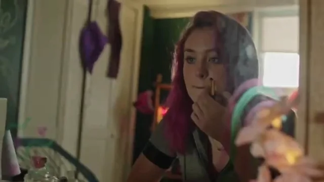 A character looks into a mirror in a room filled with personal belongings